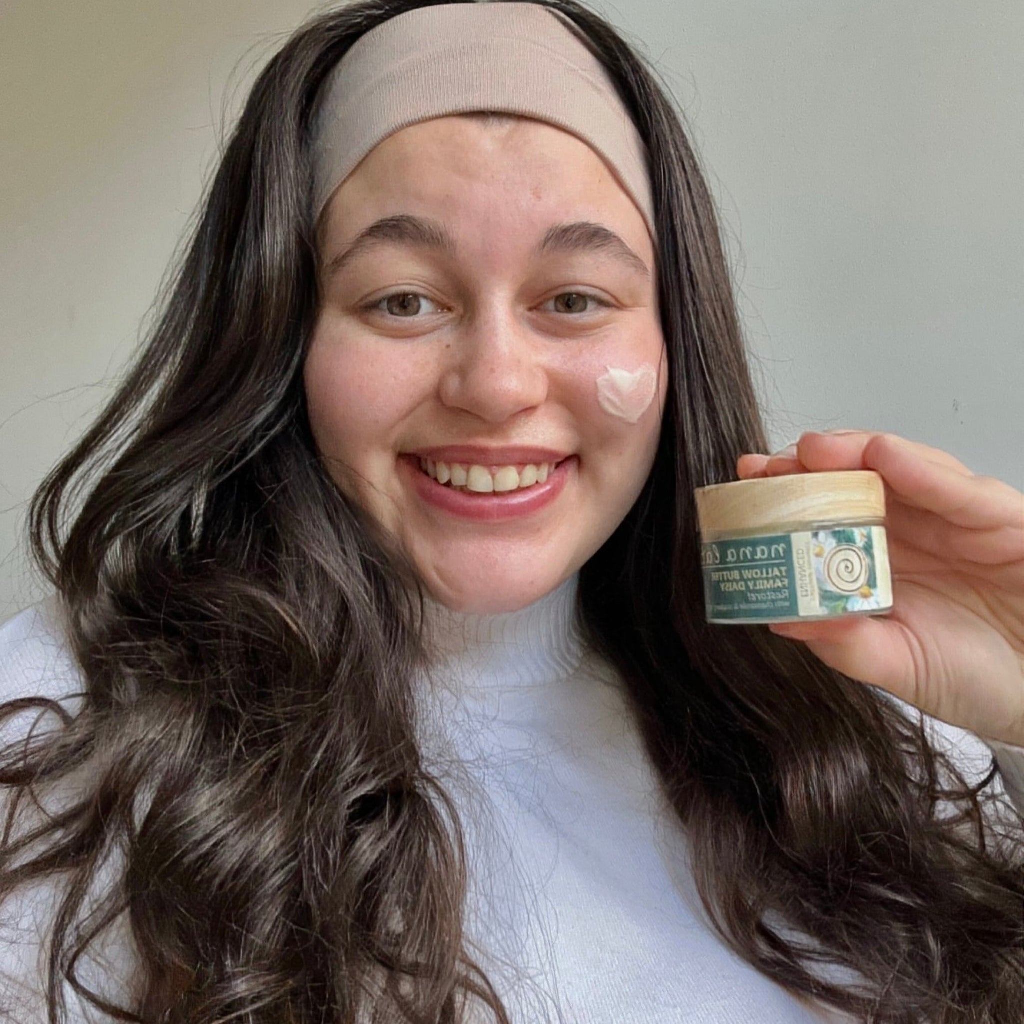 A girl with sensitive skin holding tallow cream in her hands