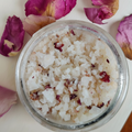 Bath salt in a glass jar with pink flower petals on a light background