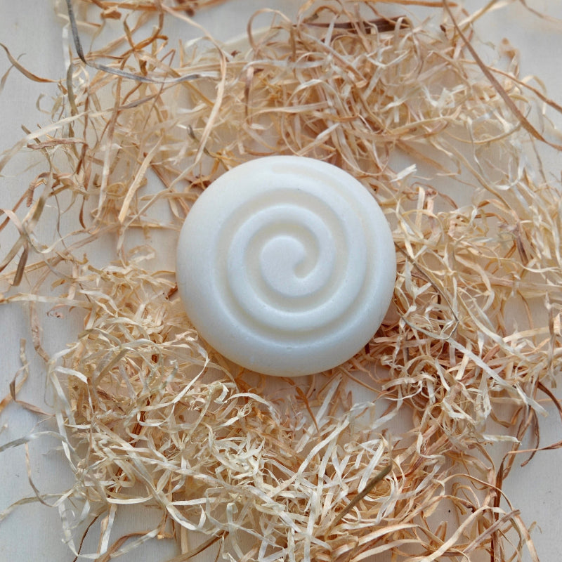 White tallow soap bar with a spiral design on a bed of straw