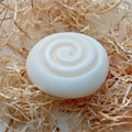 White tallow soap bar with a spiral design on a bed of straw